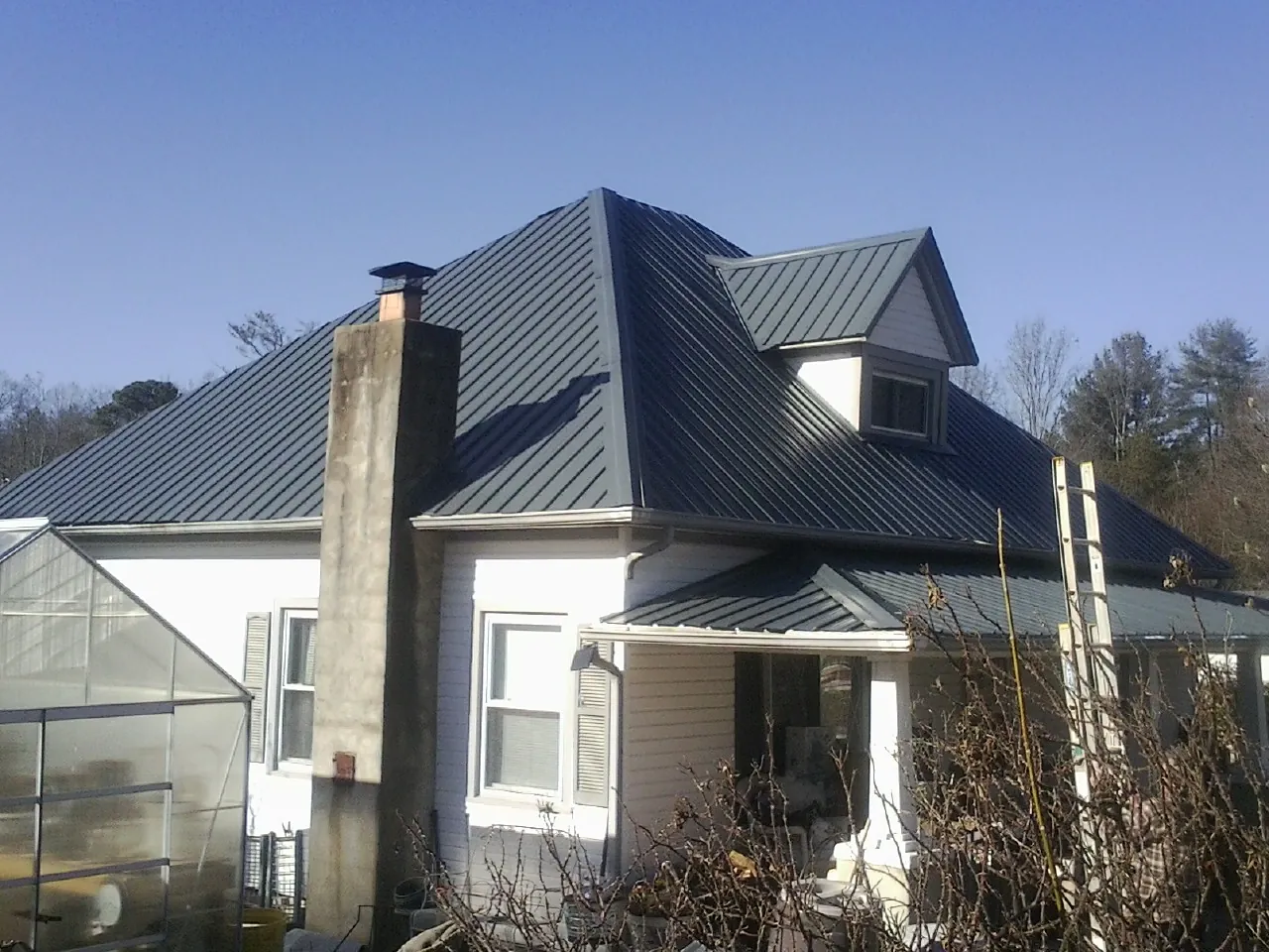 Dark blue standing seam metal roof on a white farmhouse with dormer — Slate & Tile Roof Repair by Roofing Brothers in Winona Lake