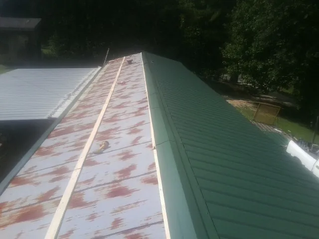 Old rusted panels beside newly installed green metal roofing — Wind Damage Roof Repair by Roofing Brothers in Winona Lake