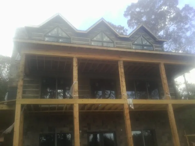 Dormers and porch framing on a large log home under construction — Roof Coating work by our crew in Winona Lake