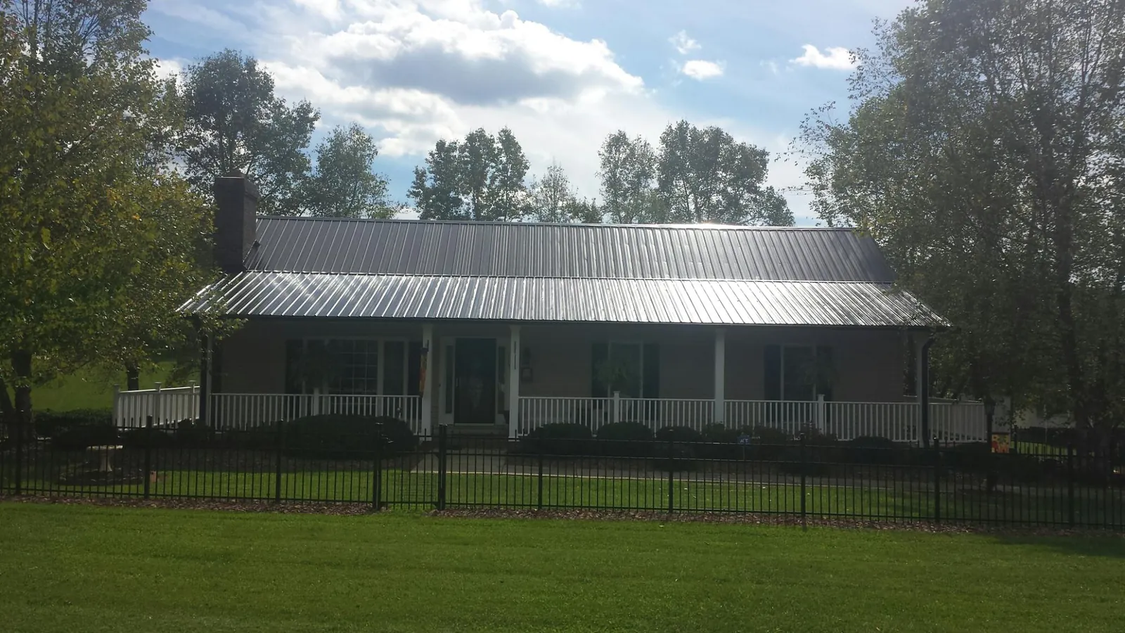 Gray metal roof on a brick ranch with a full width front porch — Gutter Guard Installation work by our crew in Winona Lake