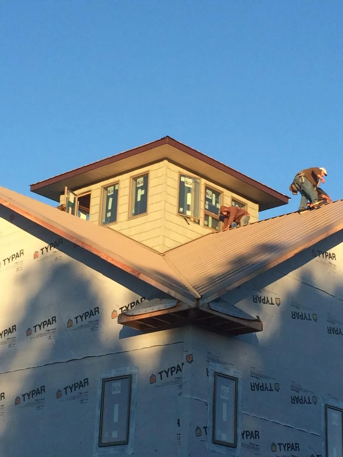 Roofers working around a rooftop cupola on a new metal roof at sunset — Roof Waterproofing in Winona Lake by Roofing Brothers